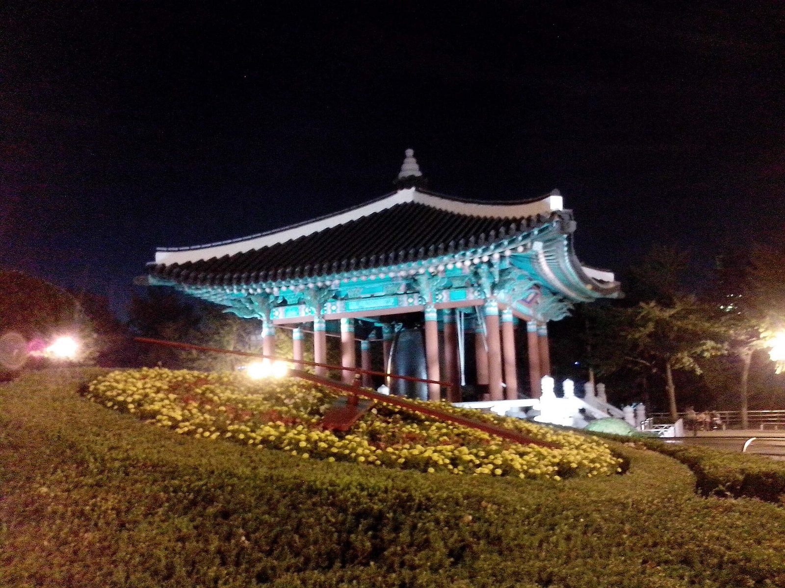 밤 조명이 켜진 종각, 앞쪽은 꽃으로 꾸민 꽃시계