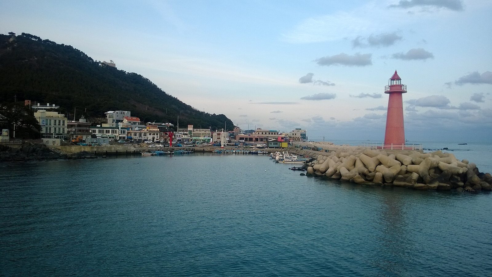 붉은 등대가 선 방파제와 포구, 산자락 아래 마을