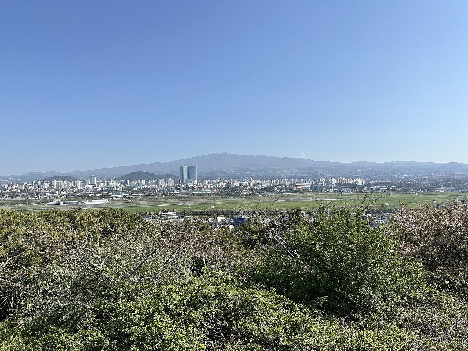 도두봉에서 내려다본 공항 활주로 너머 제주 시내와 먼 산